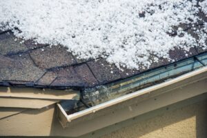 Hailstones piled on an asphalt shingle roof and gutter after a hailstorm